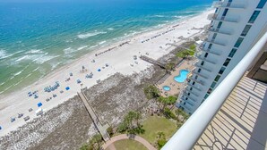 On peut admirer la plage depuis un balcon donnant sur un hôtel doté d’une piscine et de chaises longues.