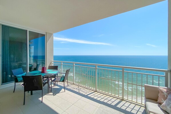 Un balcon avec une table et des chaises, un canapé et une vue sur l’océan.