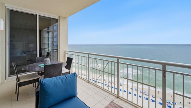 Un balcon avec vue sur l’océan, une table à manger, des chaises et un canapé.