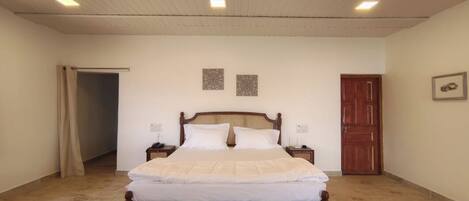 A bedroom with a wooden bed, a nightstand, a door, and a ceiling fan.