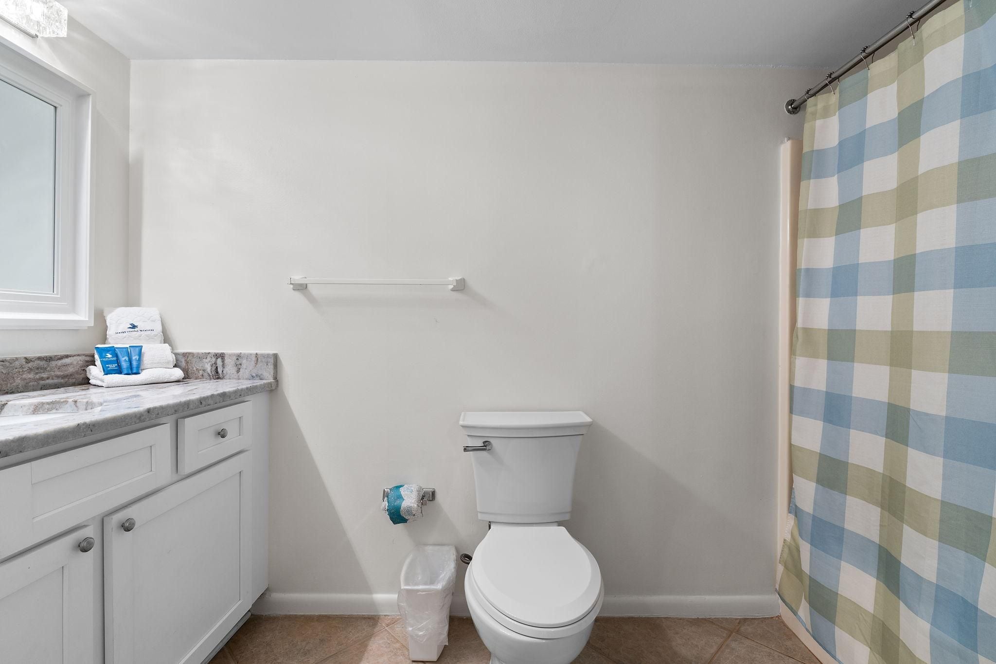 Ein Badezimmer mit Toilette, Handtuchhalter, Duschvorhang und Marmorplatte.