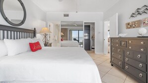 Habitación de hotel con una cama grande, un aparador, un ventilador de techo y vistas al exterior.