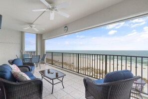 A balcony with wicker furniture, a table, and a clock. - Shipwatch A601 (Pensacola)