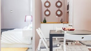 A compact hotel room with a bed, a small table with chairs, a mirror, and wall-mounted decorative plates. - Beatiful design 1 bed apt D (Sevilla)
