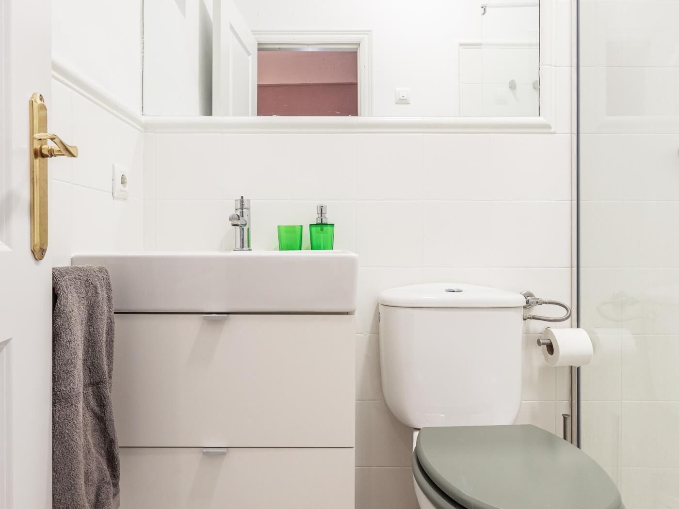 A bathroom with a toilet, sink, and a towel hanging on the wall.