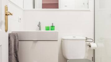 A bathroom with a toilet, sink, and a towel hanging on the wall.