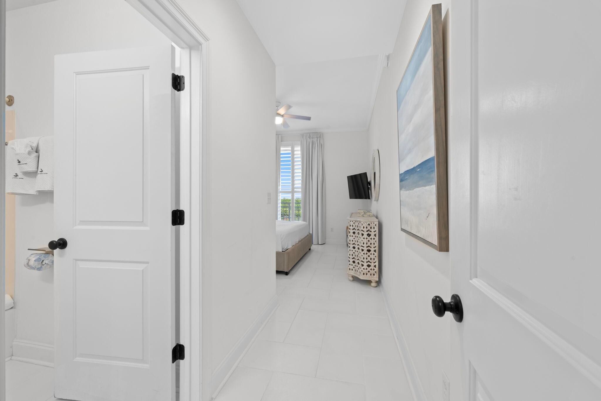 A hallway with a bed, a TV, and a painting on the wall.
