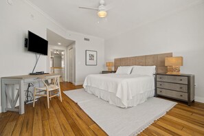 Een slaapkamer met een bed, bureau, stoel en een televisie.