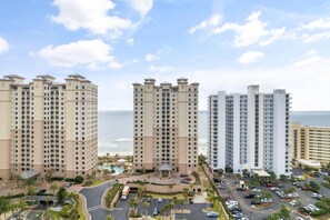 Een hoog hotel met meerdere balkons, een centrale binnenplaats en uitzicht op de oceaan.