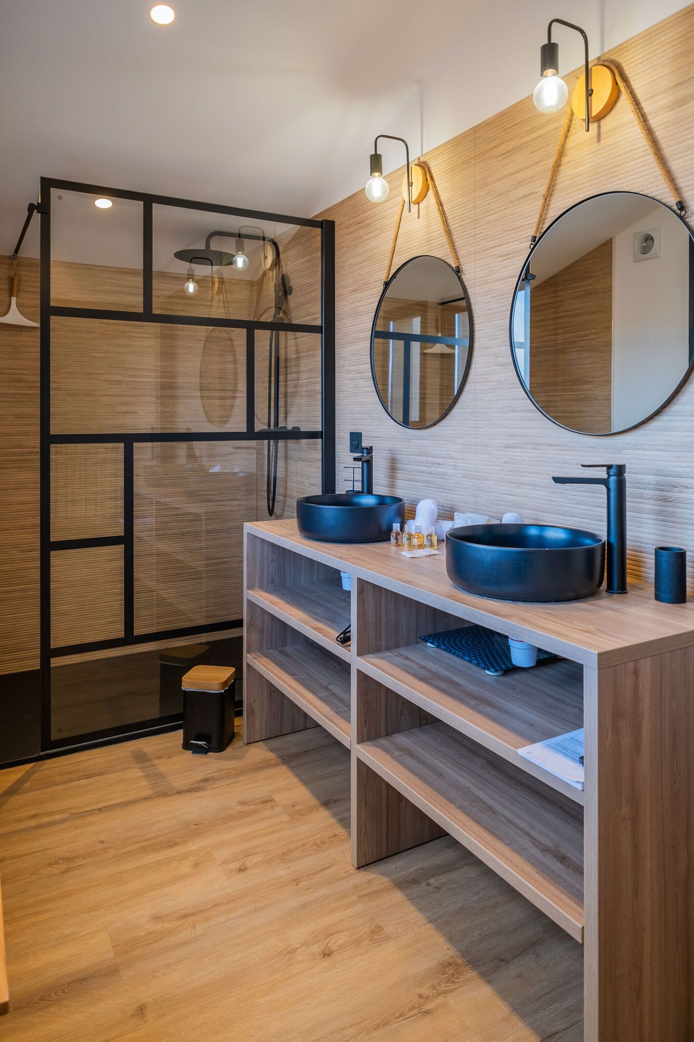 A modern bathroom with two sinks, a shower, and a mirror.