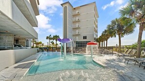 A swimming pool with water features, lounge chairs, and palm trees. - Seawind 1302 (Gulf Shores)