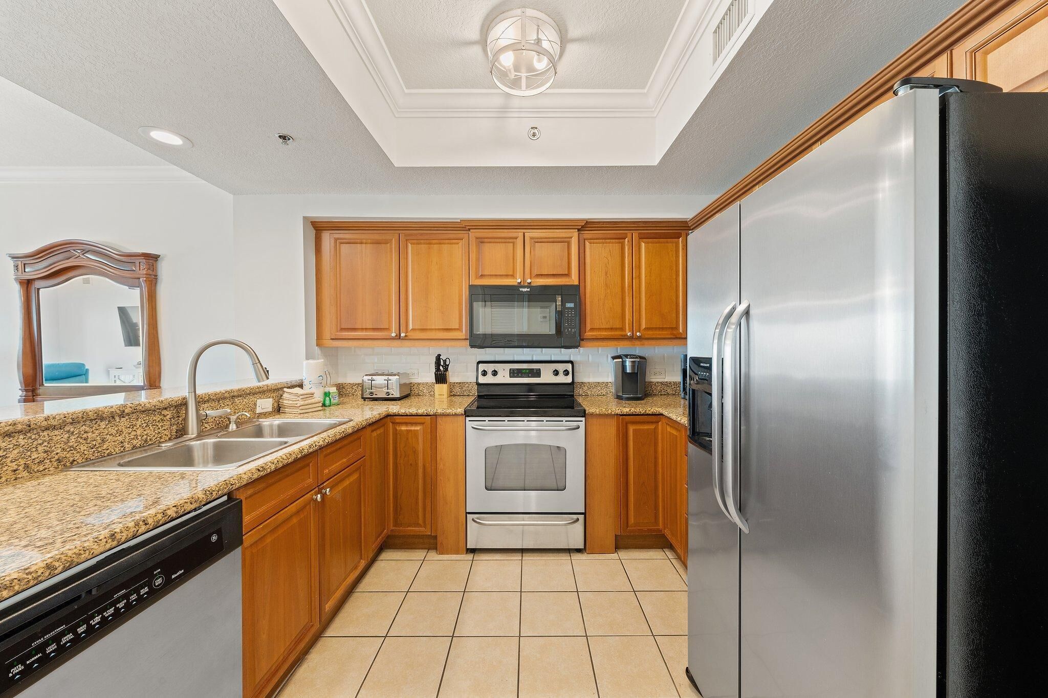 A kitchen with wooden cabinets, stainless steel appliances, a granite countertop, and a dishwasher.