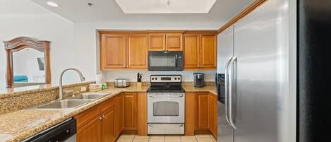 A kitchen with wooden cabinets, stainless steel appliances, a granite countertop, and a dishwasher.