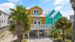 A two-story building with a balcony, surrounded by palm trees and other vegetation. - The Last Mango (Gulf Shores)