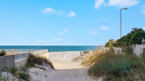 A sandy beach path leading to the ocean, with a fence and a street lamp on the right. - Romeo Beach Cottage 6 (Gulf Shores)
