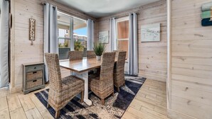 A cozy dining area with wicker chairs, a wooden table, and a 'WELCOME' sign on the wall. - Romeo Beach Cottage 6 (Gulf Shores)