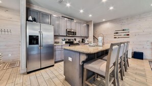 A modern kitchen with stainless steel appliances, a granite countertop, and wooden flooring. - Romeo Beach Cottage 6 (Gulf Shores)