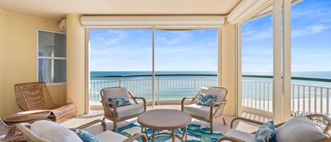 A balcony with wicker furniture and a view of the ocean.