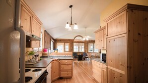 A spacious kitchen with wooden cabinets, a central island, and a modern stove. - Cottage Beside Crystal Beach - 3BR & BBQ! (Fort Erie)