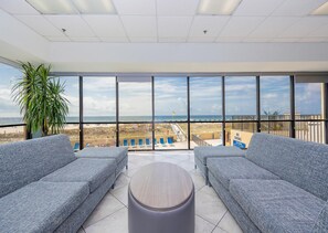 A balcony with a view of the beach, two grey sofas, a round table, and a potted plant. - Phoenix V 102 (Orange Beach)