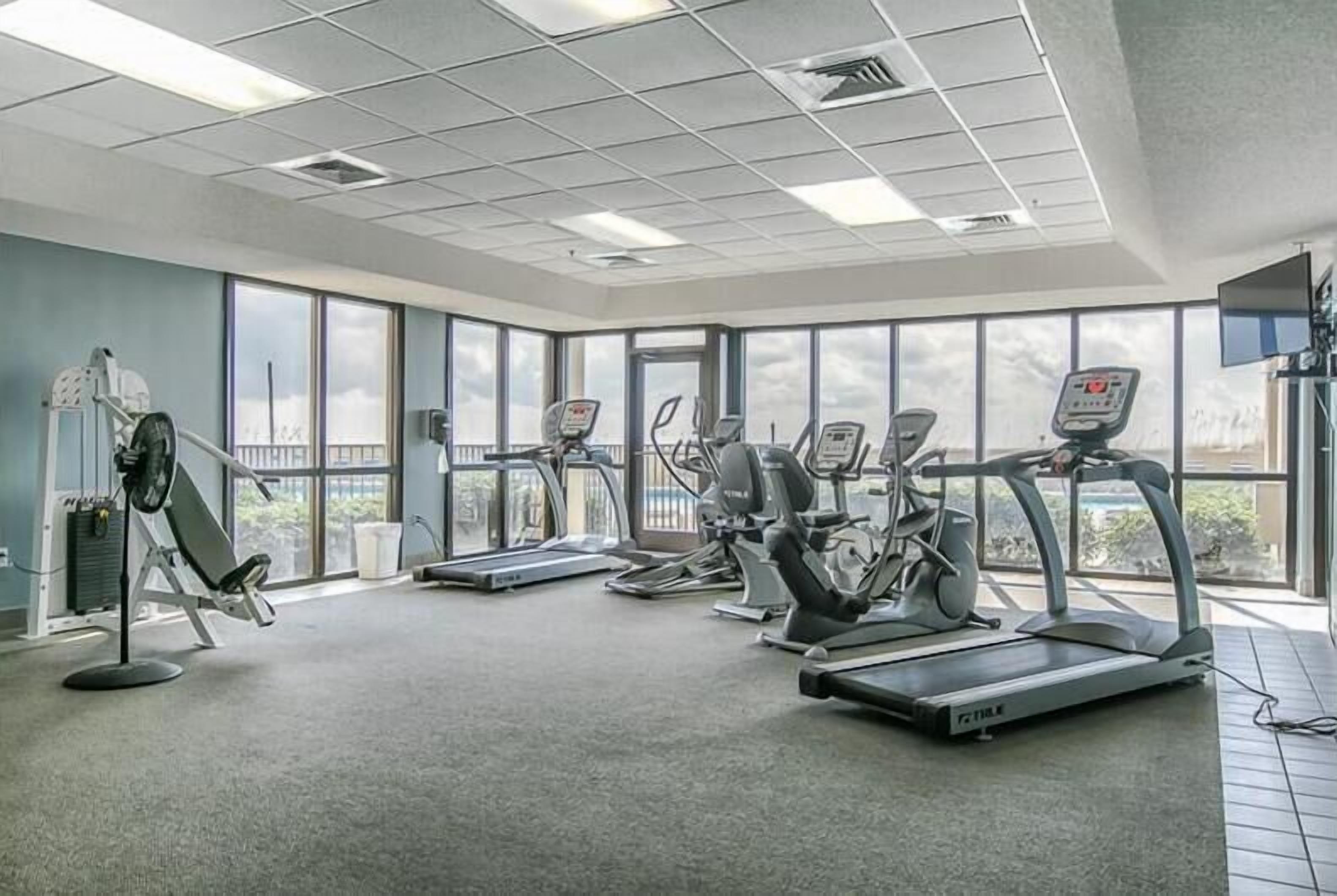 Ein Fitnessraum mit Laufbändern, Crosstrainern und einem Ergometer.
