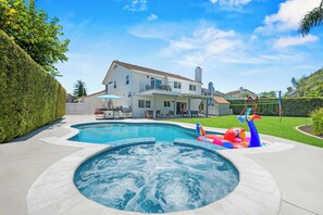Ein Wohnhaus mit Pool, Whirlpool und einem Garten mit Terrasse.