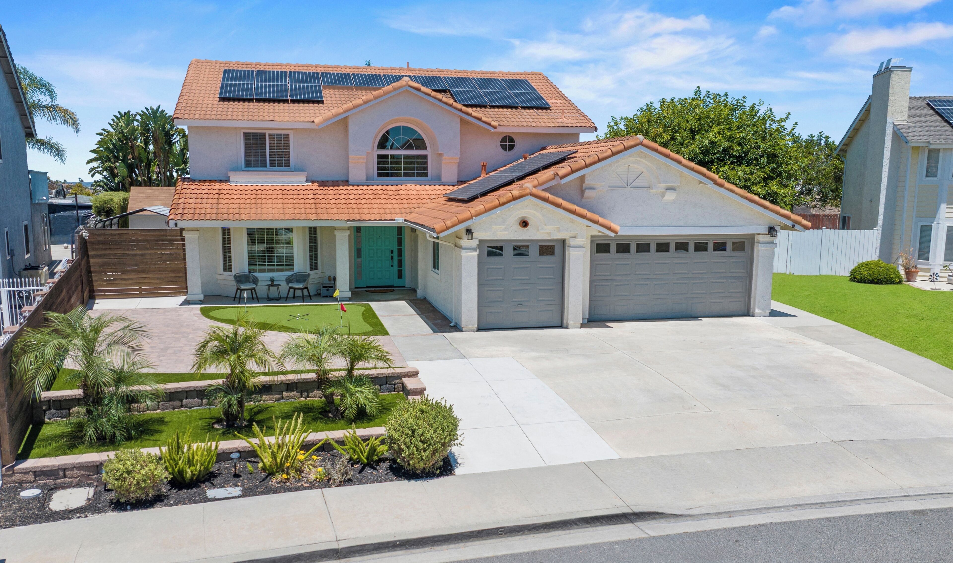 A two-story house with a garage, solar panels, and a well-maintained lawn.