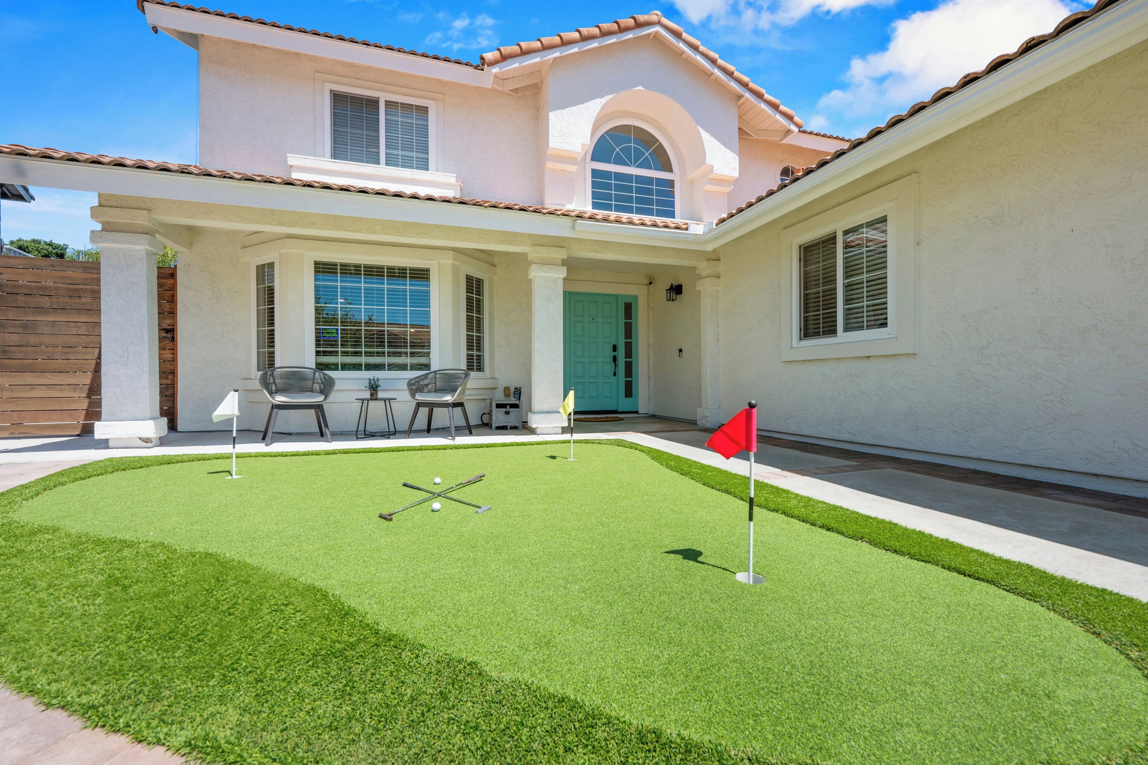 A house with a patio area featuring a lawn, a flag, and a table with chairs.