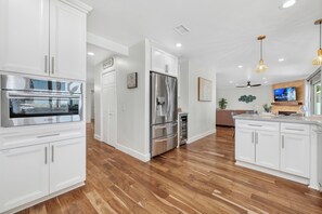 Una cocina moderna con armarios blancos, electrodomésticos de acero inoxidable y piso de madera.