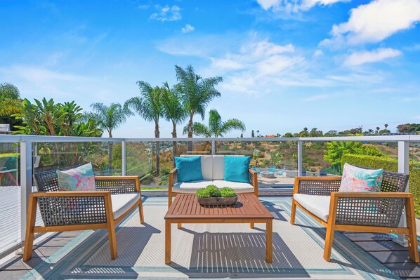 Terraza con mobiliario exterior, vista a palmeras y cielo despejado.