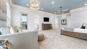 A spacious bedroom with a large bed, a sofa, and a chandelier. - Battery 17 (Orange Beach)