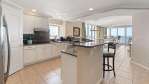 A spacious kitchen with white cabinets, a granite countertop, and a large island. - Colonnades 1601 (Gulf Shores)
