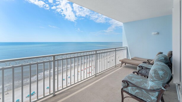 A balcony with a view of the beach and ocean. There are lounge chairs and a small table. - Colonnades 1601 (Gulf Shores)