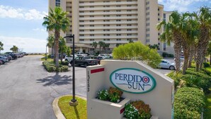 A hotel entrance with a sign reading "Perido Sun" and a parking lot with several cars. - Perdido Sun 610 (Pensacola)