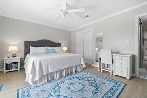 Una camera da letto con un letto, comodini, una scrivania, una sedia, un armadio e una ventola a soffitto.