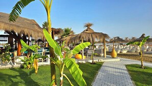 A resort with thatched-roof structures, a paved walkway, and lush greenery. - Perla Penthouse (Ishëm)