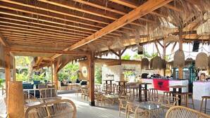 An outdoor café with wooden furniture and a thatched roof. - Perla Penthouse (Ishëm)