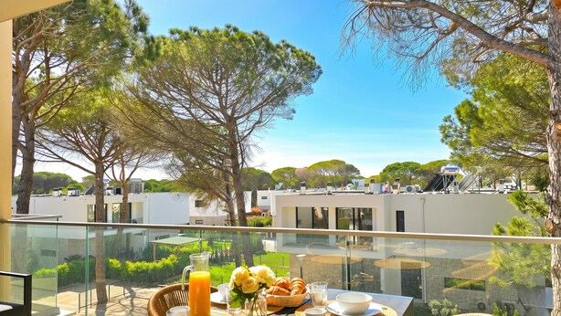 A balcony with a breakfast setup including bread, eggs, and juice, overlooking a modern building and greenery. - Aqua Bliss Apartment 296 (Ishëm)