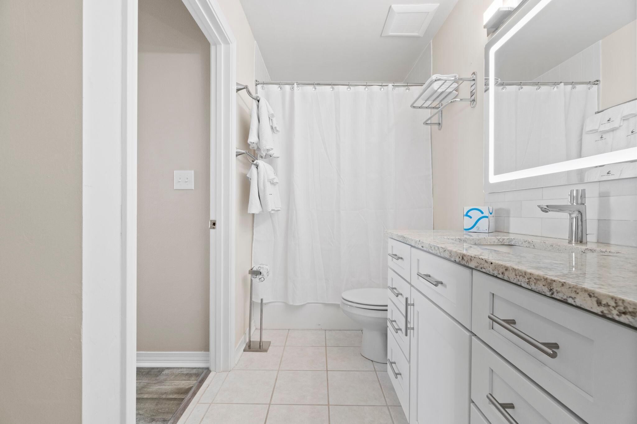 Une salle de bain moderne équipée d’une douche, de toilettes et d’un meuble-lavabo avec un miroir.