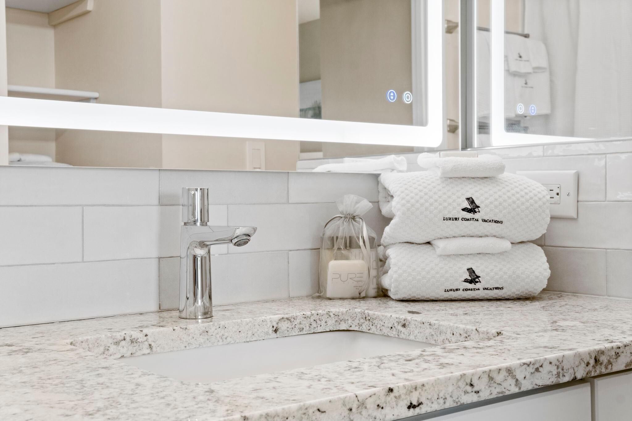 Une salle de bain avec un lavabo en marbre, un miroir et un porte-serviettes avec des serviettes pliées.