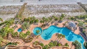 Un resort con una amplia zona de piscina, palmeras y una playa.
