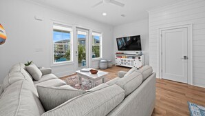 A modern living room with a sectional sofa, a coffee table, and a flat-screen TV. - Totally Beachin' at Pelican Place (Gulf Shores)