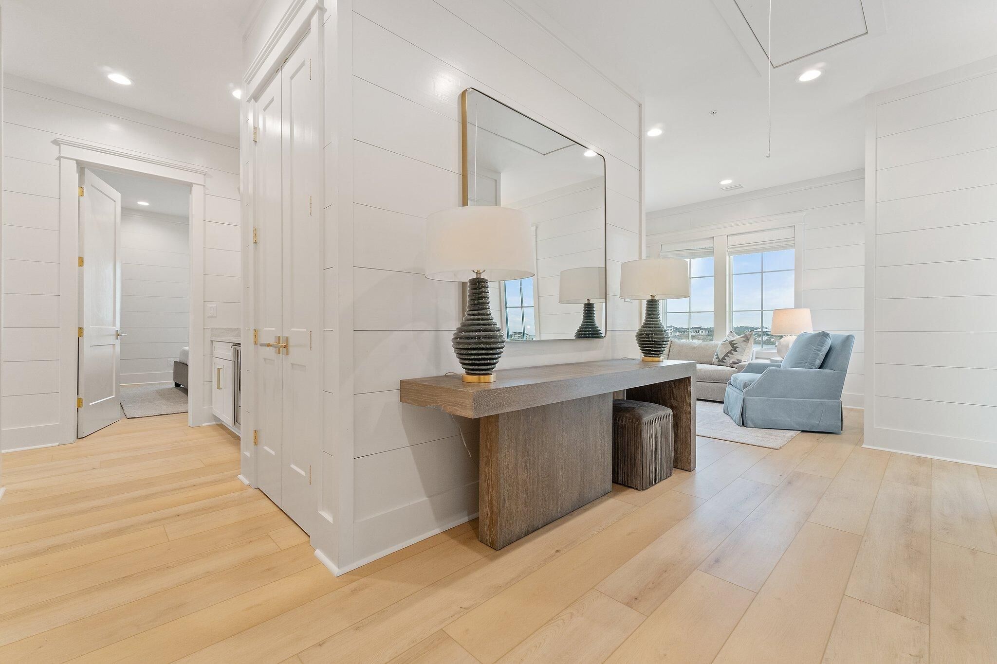 Una sala de estar moderna con piso de madera, un espejo grande y un sofá azul claro.