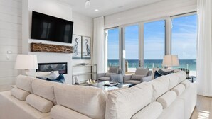 Ein modernes Wohnzimmer mit großem Flachbildfernseher, bequemen Sitzgelegenheiten und Meerblick.