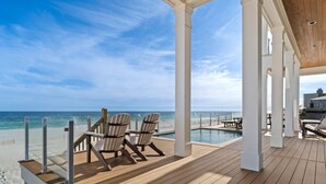Eine Holzterrasse mit Pool, Liegestühlen und Meerblick.