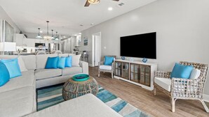 A modern living room with a sofa, two wicker chairs, a television, and a ceiling fan. - Riviera Dunes 302 (Pensacola)