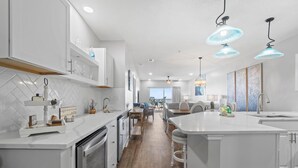 A modern kitchen with white cabinetry, a central island, and pendant lighting. - Riviera Dunes 302 (Pensacola)