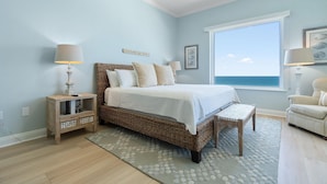 A bedroom with a large window, a bed, a bedside table, a chair, and a rug. - Indigo East 2002 With Private Poolside Cabana! (Pensacola)
