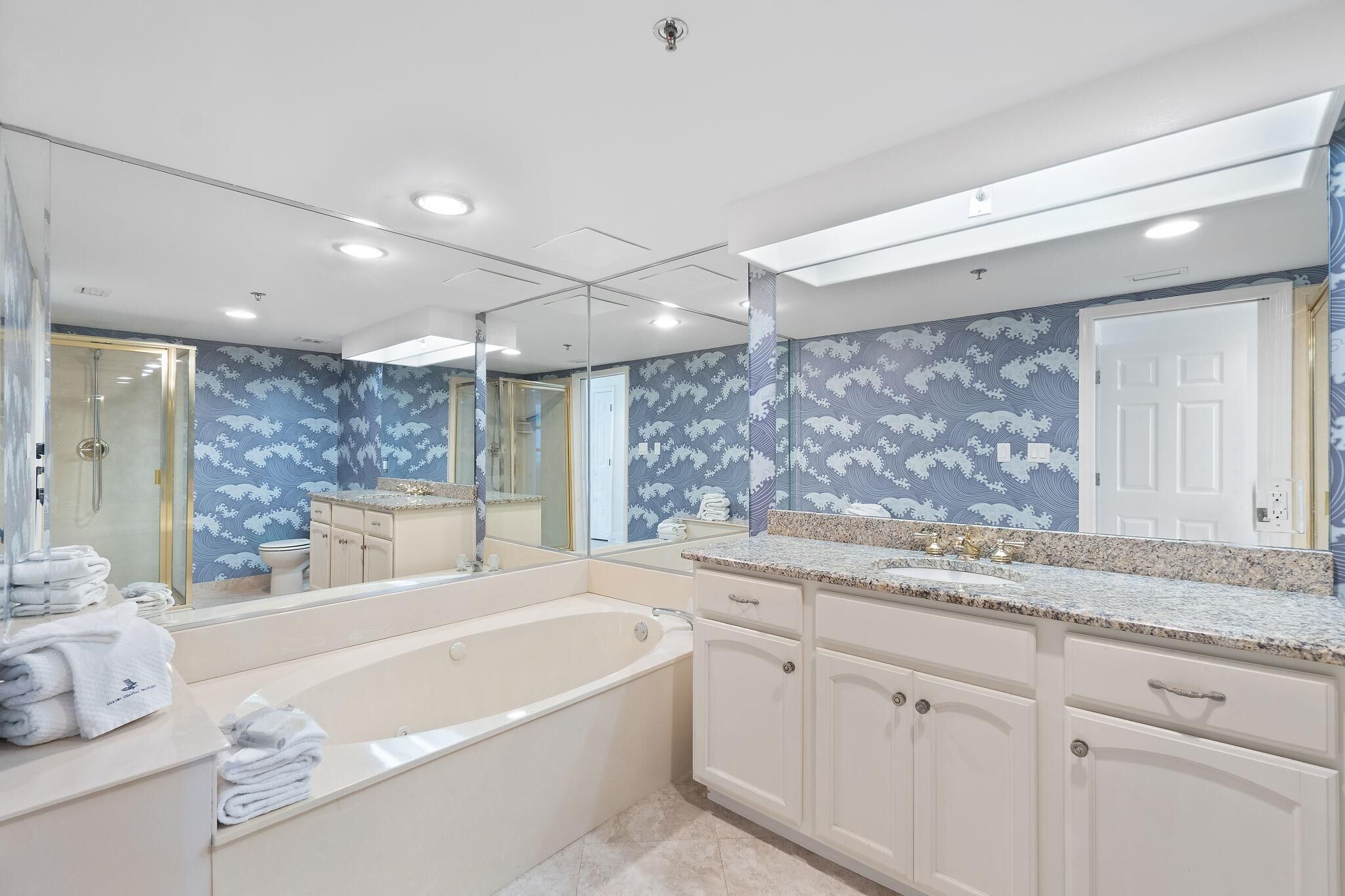 A modern bathroom with a large mirror, a bathtub, and a vanity with a sink.