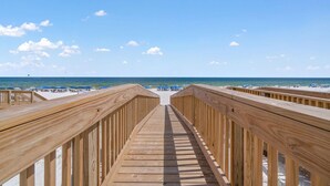 A wooden boardwalk leading to a beach with umbrellas and people. - The Bluffs #6 - Coastal Bliss (Orange Beach)